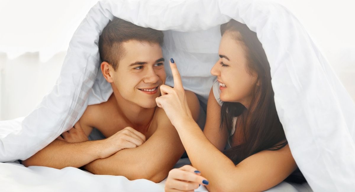 A photo of a couple on the bed happily interacting with each other.