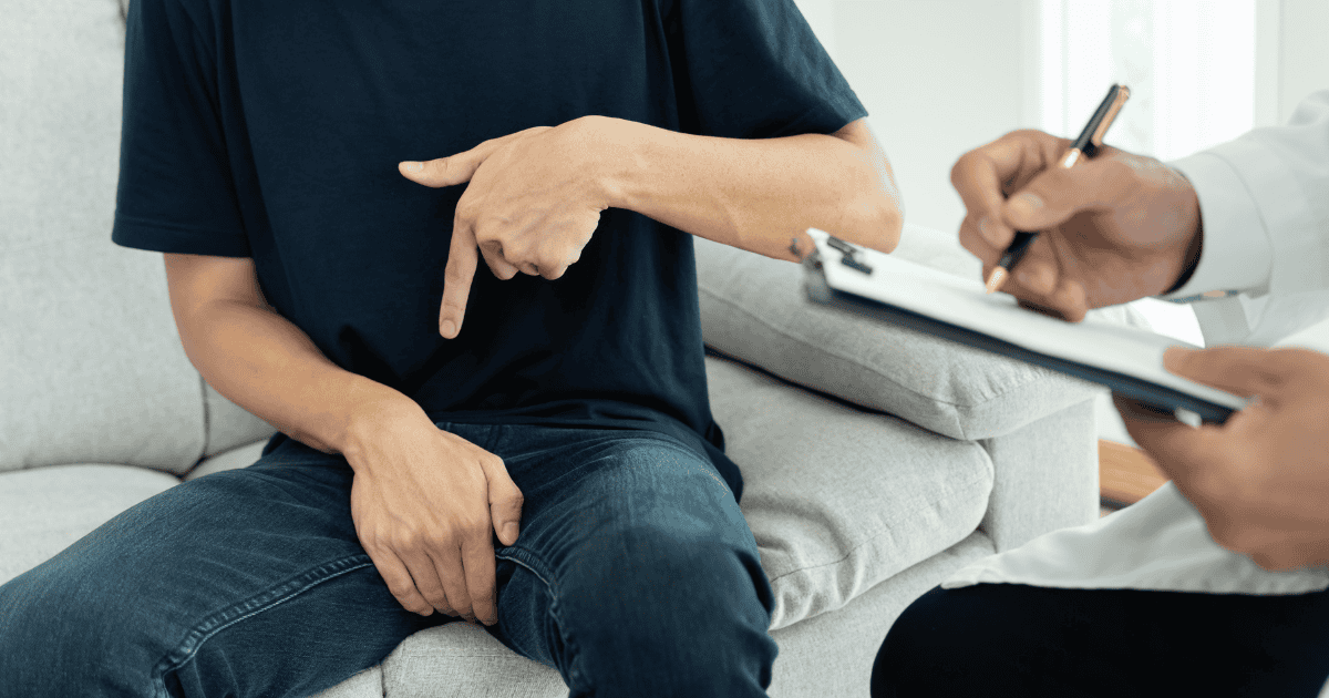 A man talking to a doctor while clutching his penis